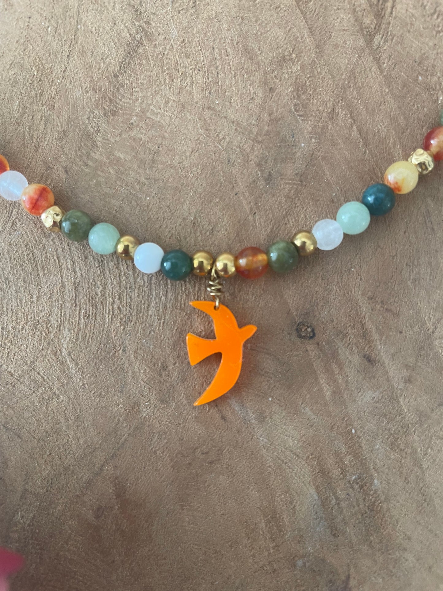 Gros plan breloque orange oiseau et perles orange vert naturelles