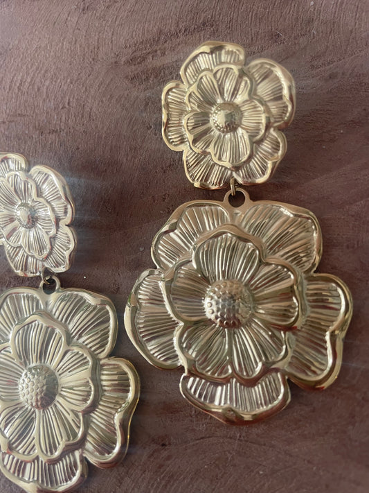 zoom sur les détails grosses boucles d'oreilles fleurs dorées gros bijou