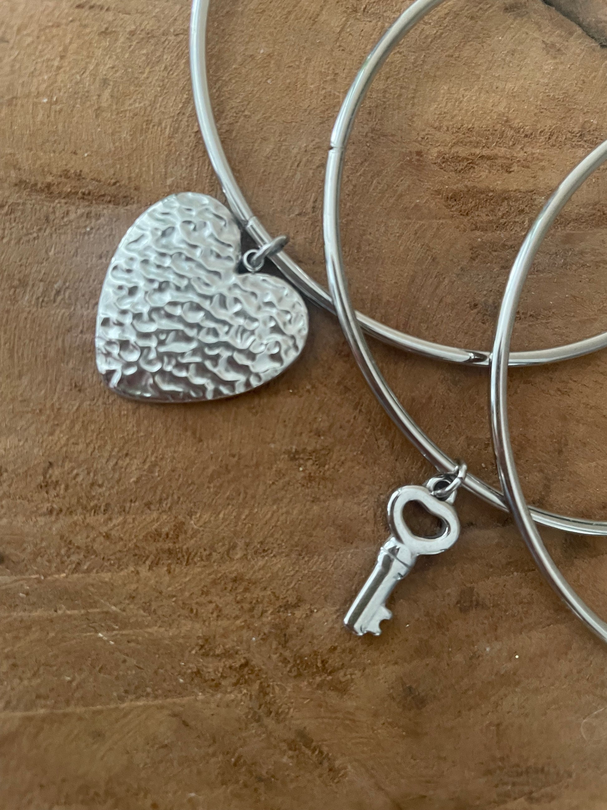 Gros plan breloque coeur et clef bracelets joncs argent