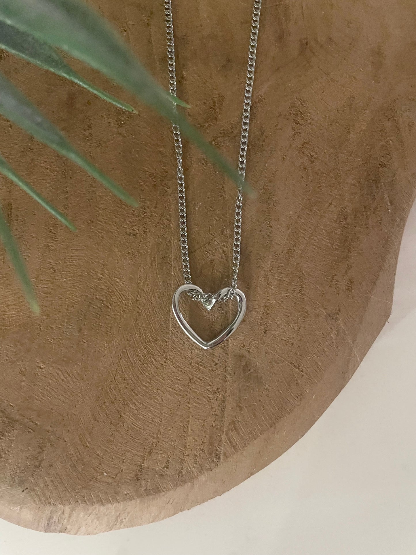 zoom détail petit pendentif coeur ouvert argent sur fond bois