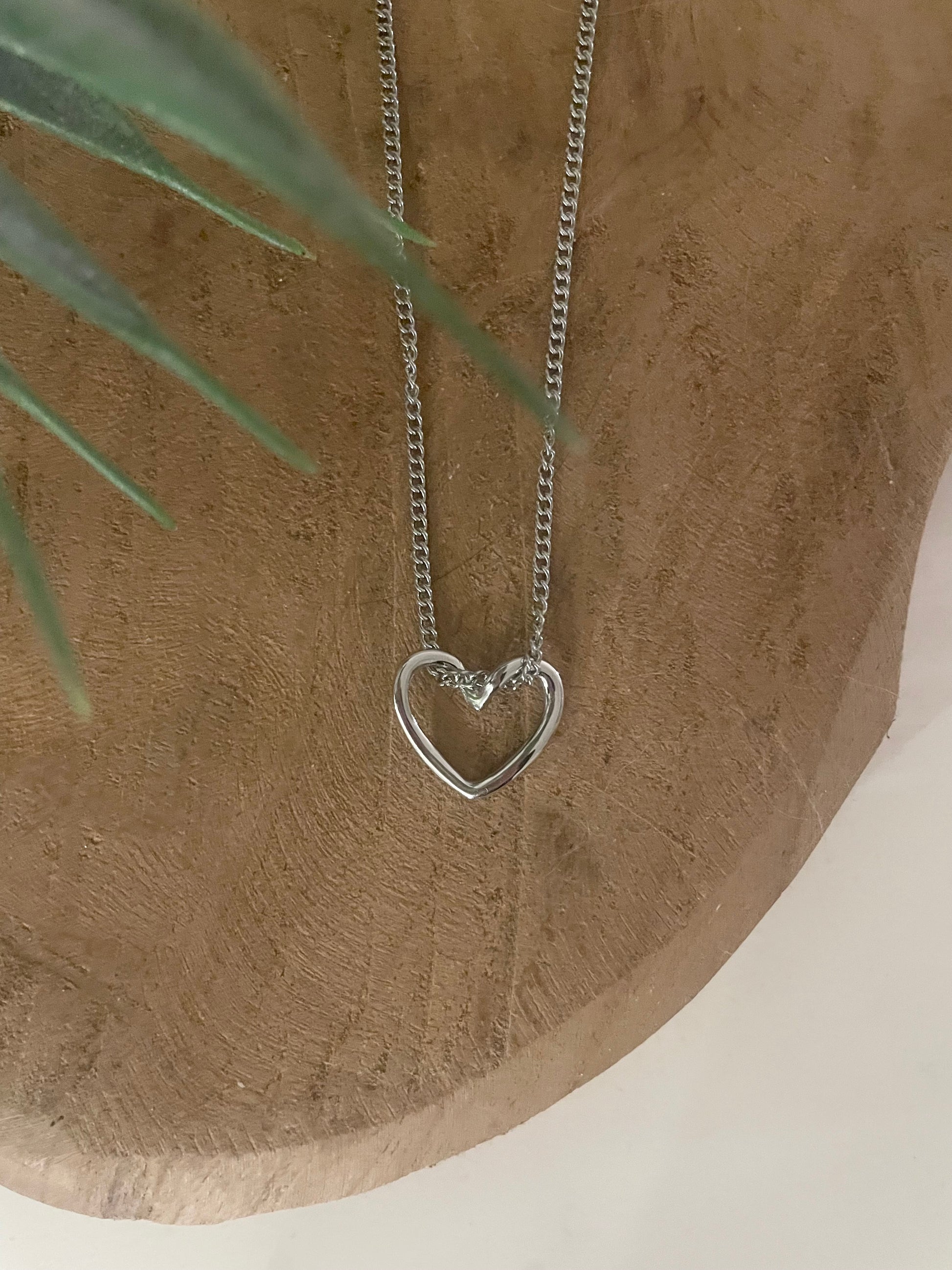 zoom détail petit pendentif coeur ouvert argent sur fond bois