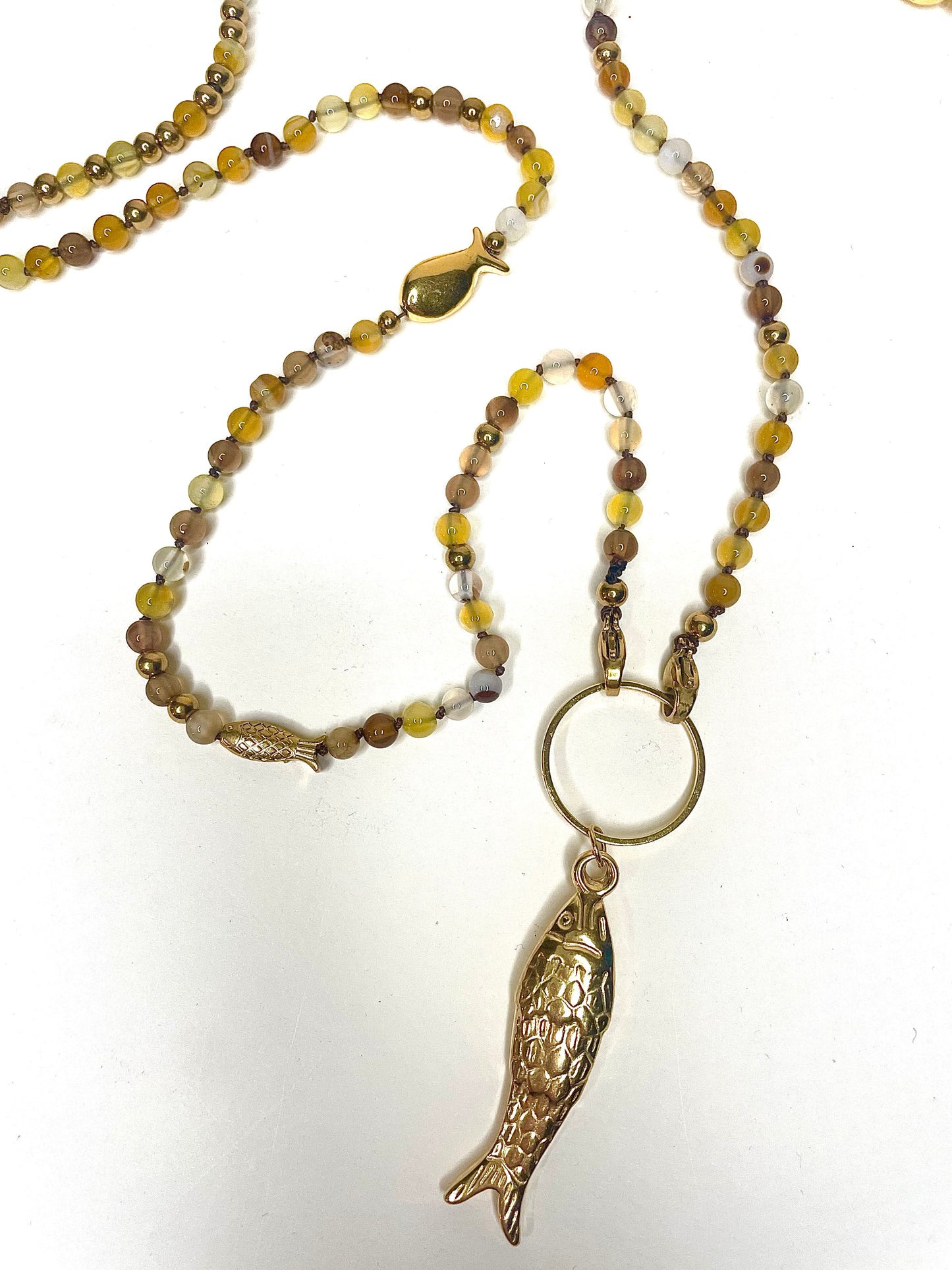 Zoom fond blanc grand pendentif poisson acier inoxydable doré du collier sautoir Jacqueline tons jaune marron
