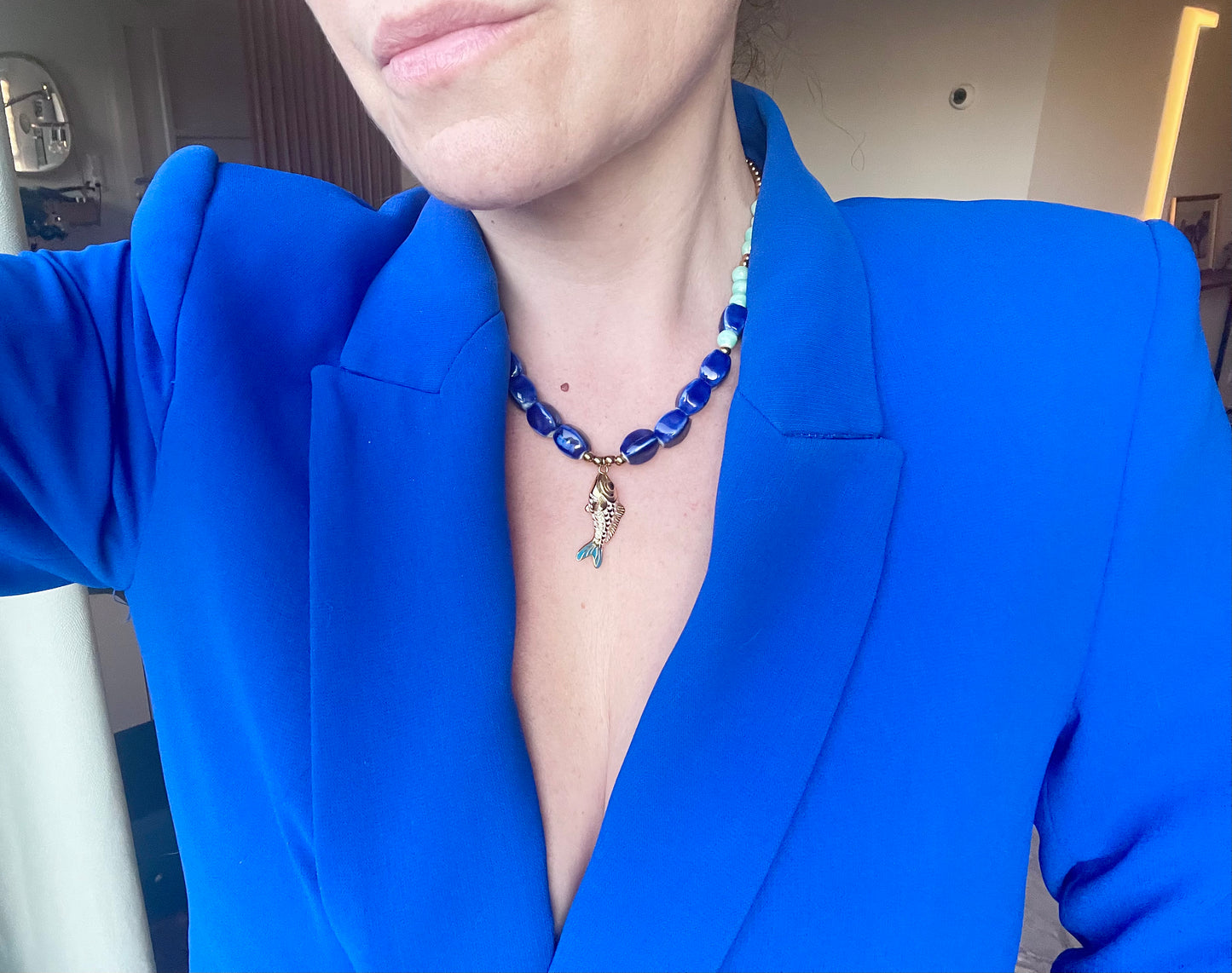 Collier artisanal bleu marine porté avec blazer style moderne