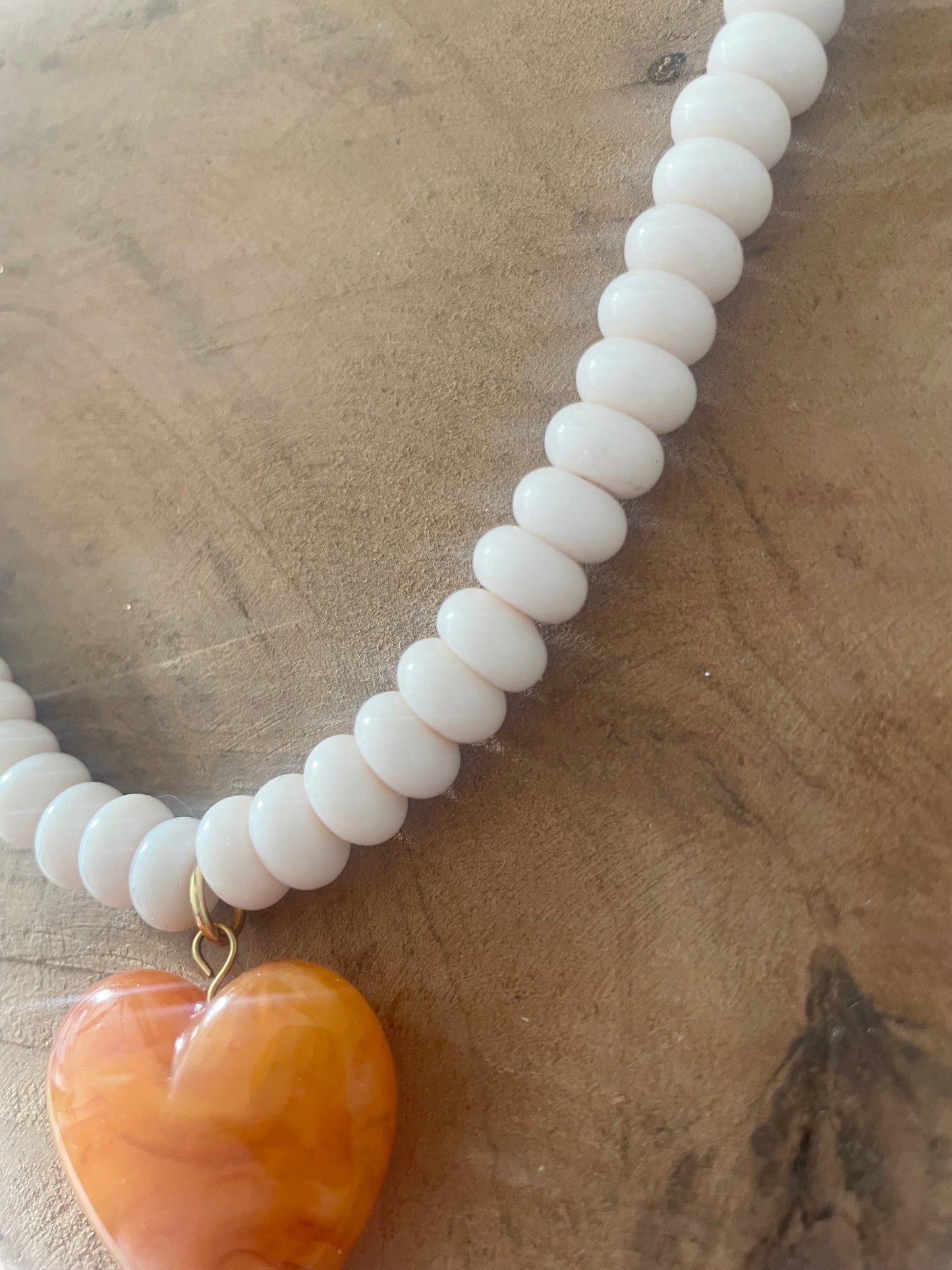 Détail perles en verre ivoire du collier coeur orange ambré été 2026