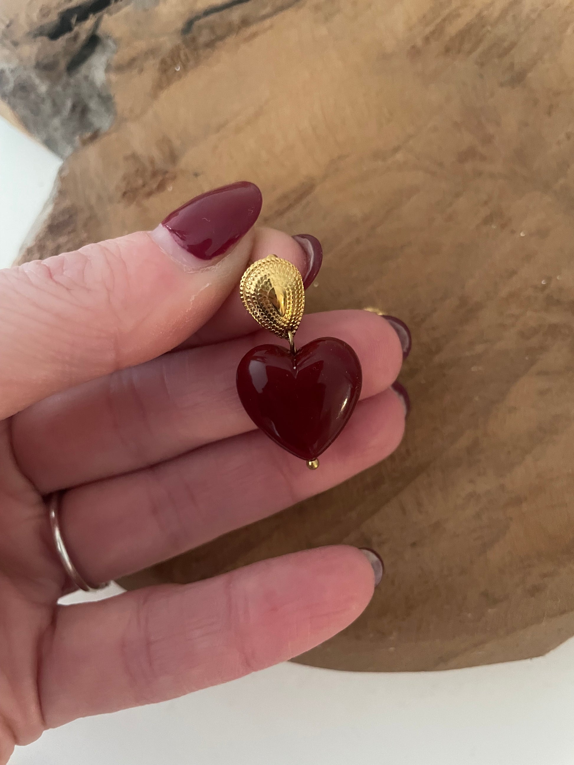 Gros plan détail petites boucles d’oreilles coeur bordeaux et doré