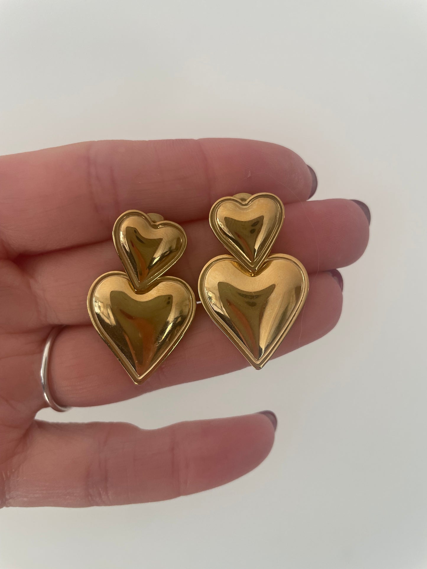 Détail gros plan boucles d’oreilles double coeur version dorée acier inox