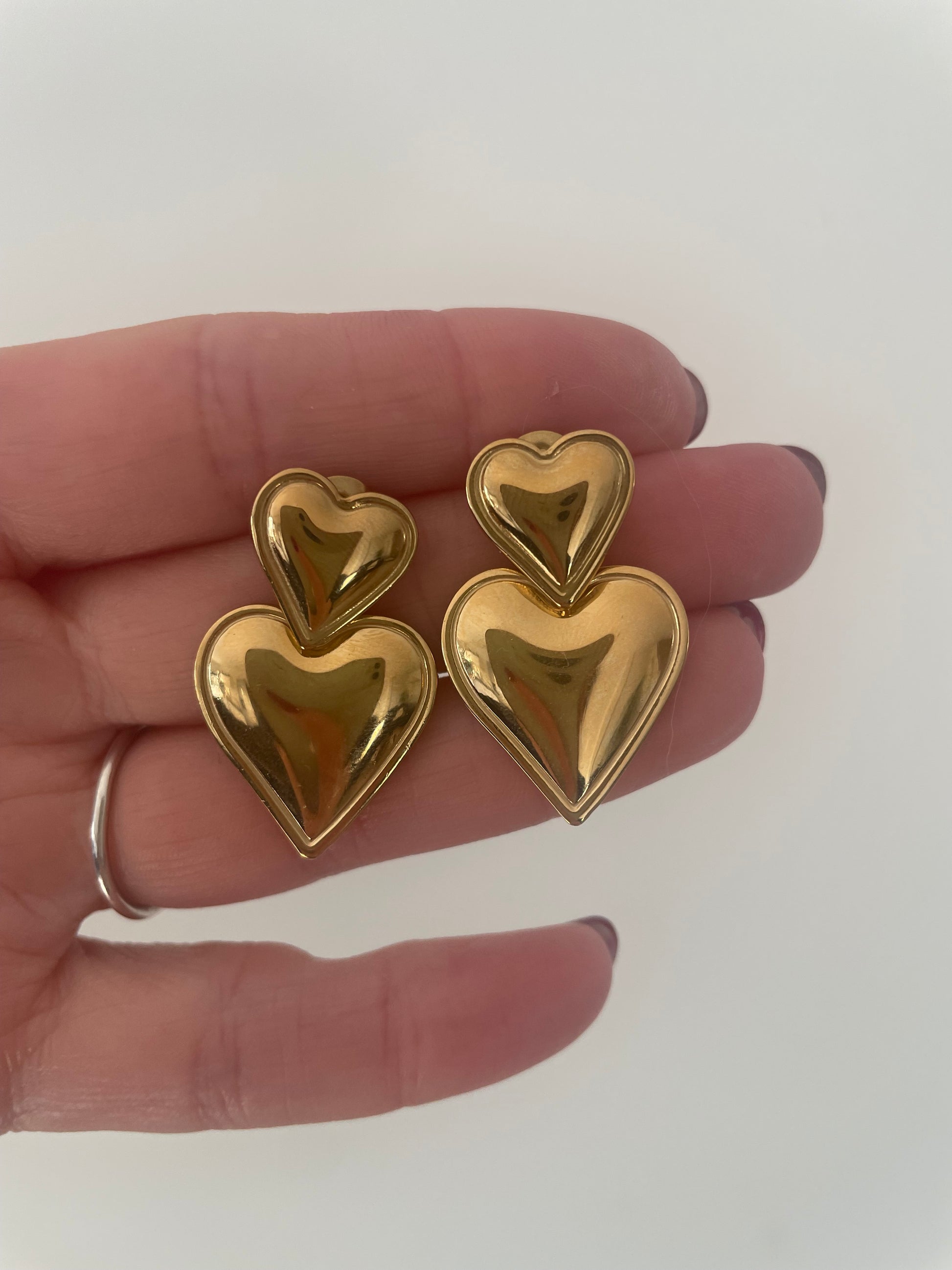Détail gros plan boucles d’oreilles double coeur version dorée acier inox