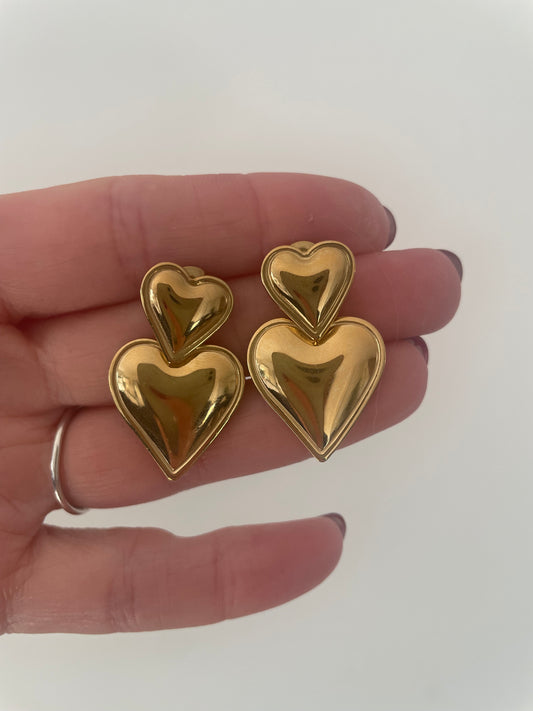 Détail gros plan boucles d’oreilles double coeur version dorée acier inox